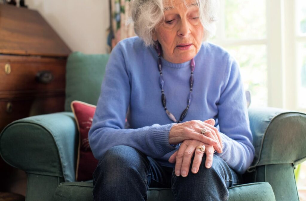 An older adult woman rubbing her sore hands due to Parkinson's disease