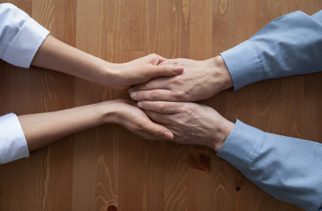 a pair of young hands hold the hands of a senior in support