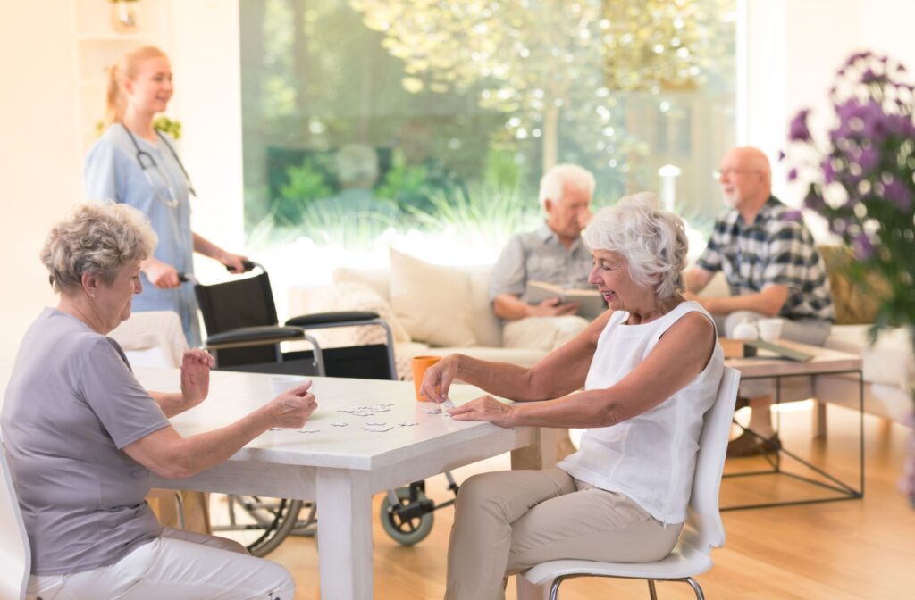 a group of seniors play a card game while sitting around a table at a respite care community