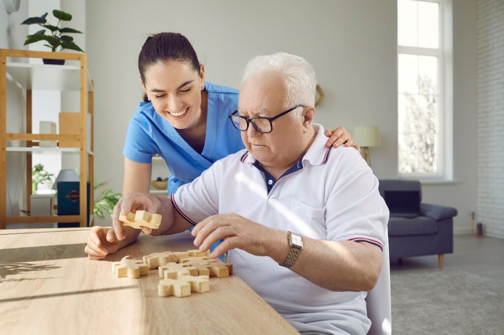 A caregiver helps a senior with a wooden puzzle in memory care.