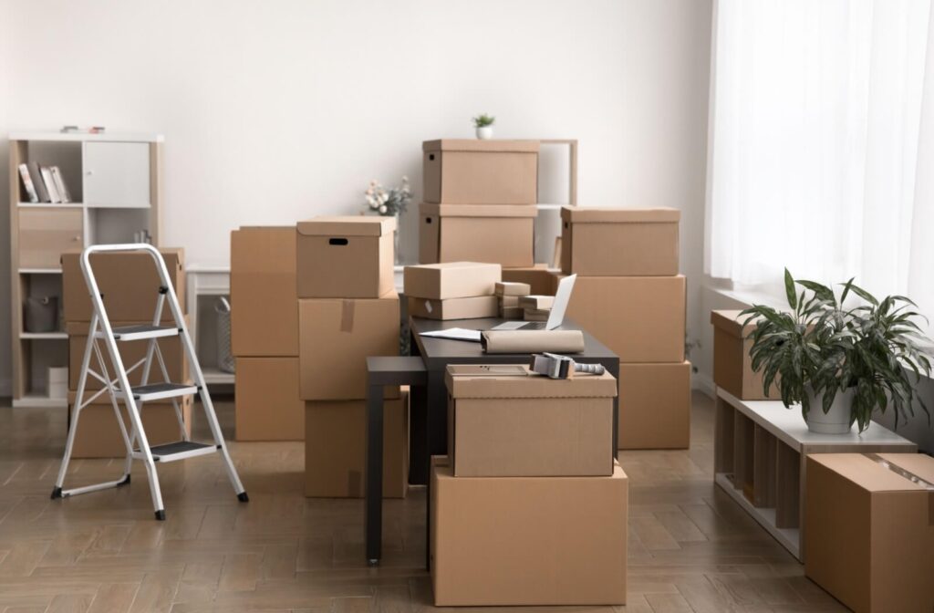 Several piles of packed-up boxes and belongings sit in a home office