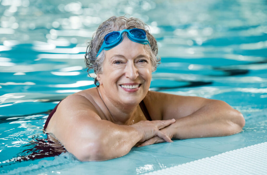a senior woman smiles from inside a pool